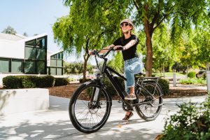 Femme à vélo électrique prête à aller au travail depuis son quartier résidentiel